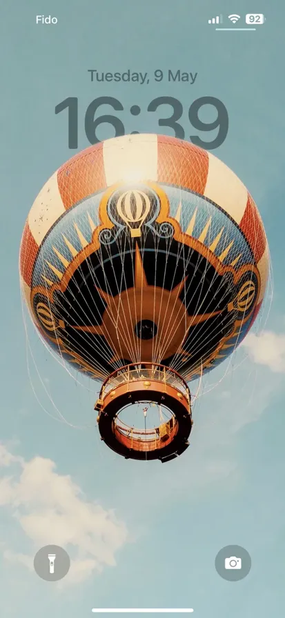 A white and orange hot air balloon floating in the clear blue sky