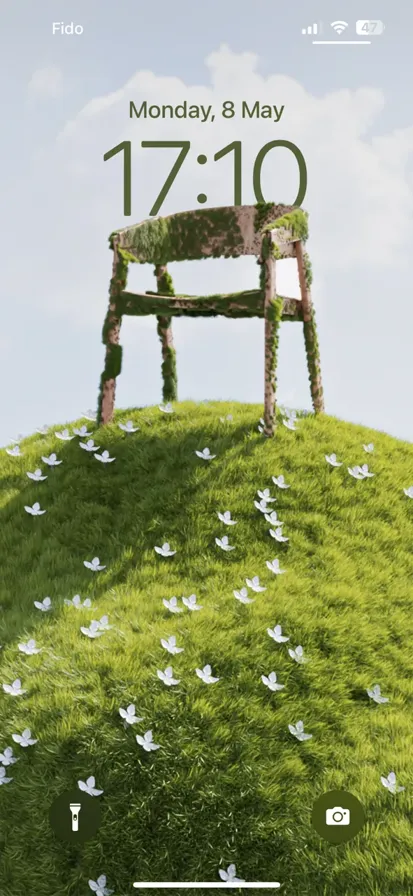 A green hill with a chair sitting on top, under a blue sky