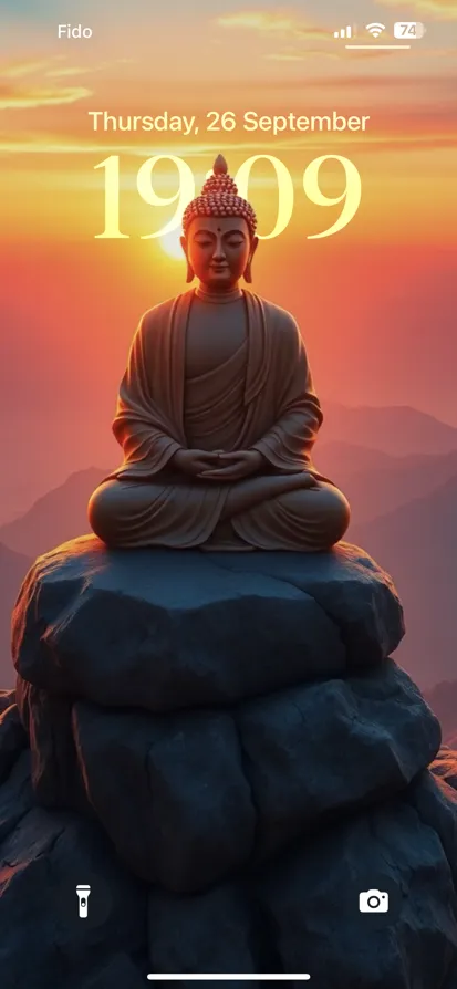 Buddha statue on rock, sunset hues, peaceful scene.