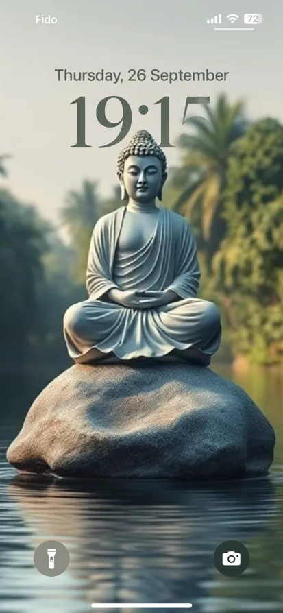 A tranquil scene of a Buddha statue reflected in calm water, surrounded by lush greenery.