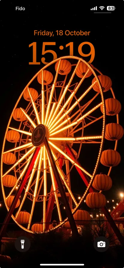 Bright ferris wheel at night with pumpkins and lights.