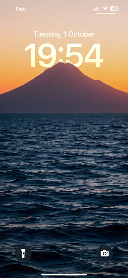 A tranquil dusk scene featuring a silhouetted mountain and reflective water.