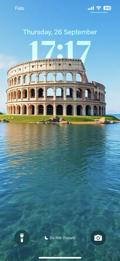 A coliseum-like structure on a grassy island surrounded by blue water.