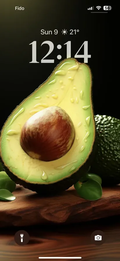 A green avocado that is open and it is on the table.