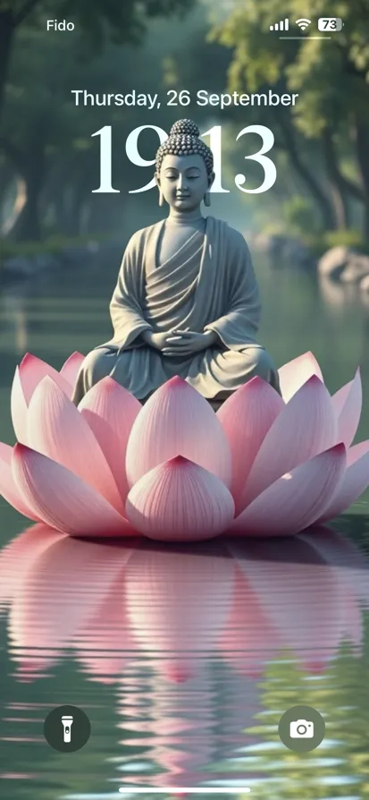 A serene Buddha statue on a pink lotus in calm waters.