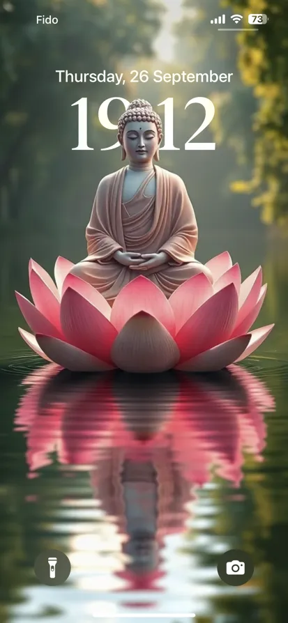 A serene Buddha statue meditates on a pink lotus flower surrounded by greenery.